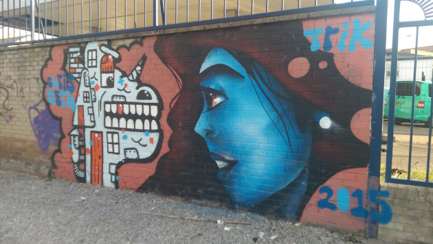 Mural of a crocodile like creature with a horn next to a blue skinned woman with long dark hair